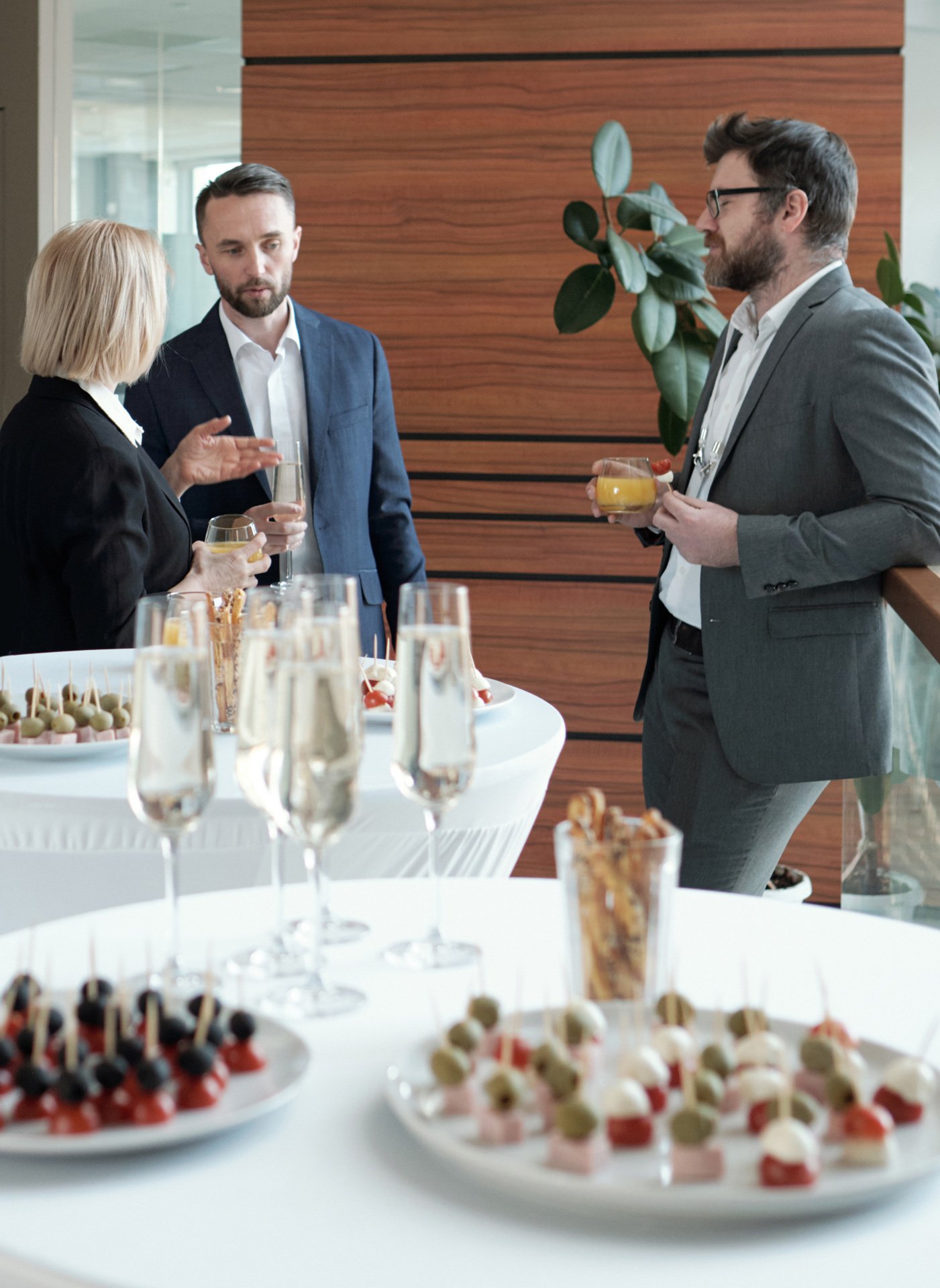 two groups successful speakers formalwear talking by served tables