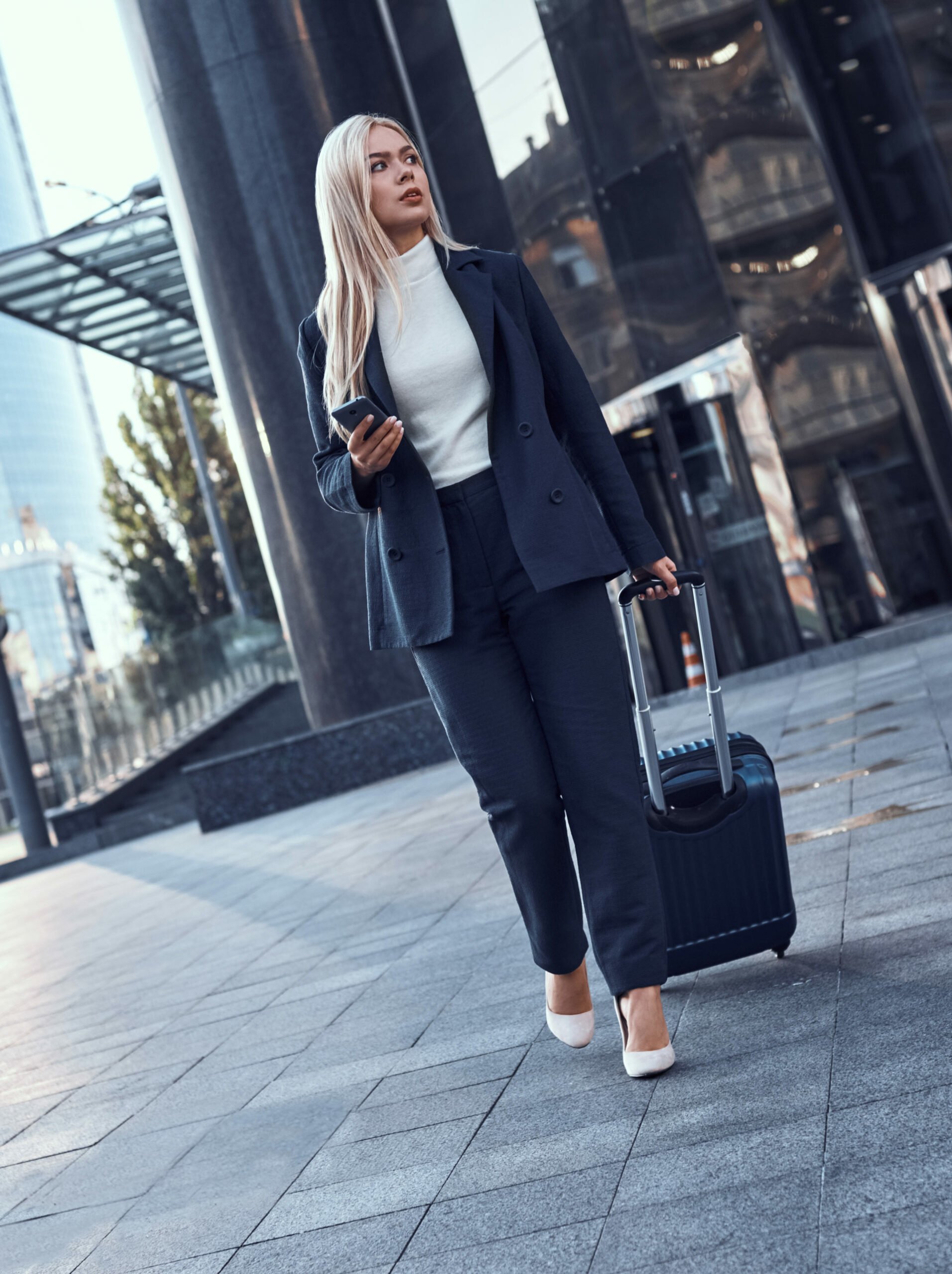 full length portrait smiling successful businesswoman pulling suitcase